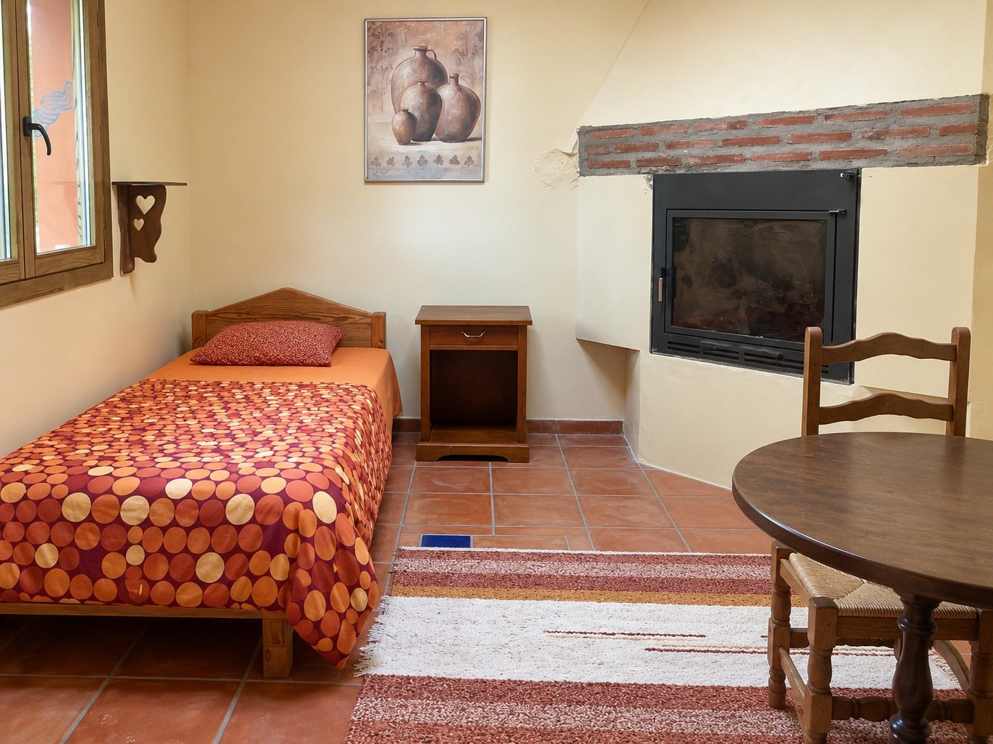 La Roja — By the fireplace, a bed and the table